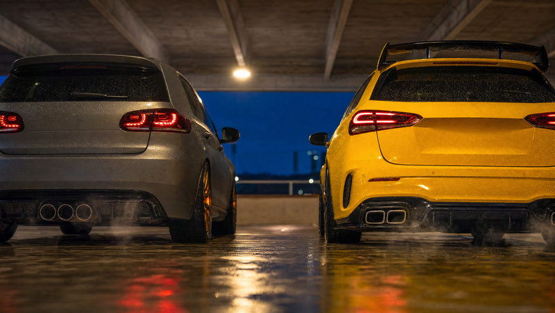 Deux compactes sportives radicales vues de l'arrière côte à côte au crépuscule, comparatif Audi RS3 et Mercedes A45 AMG, doubles sorties d'échappement et disques de frein chauds