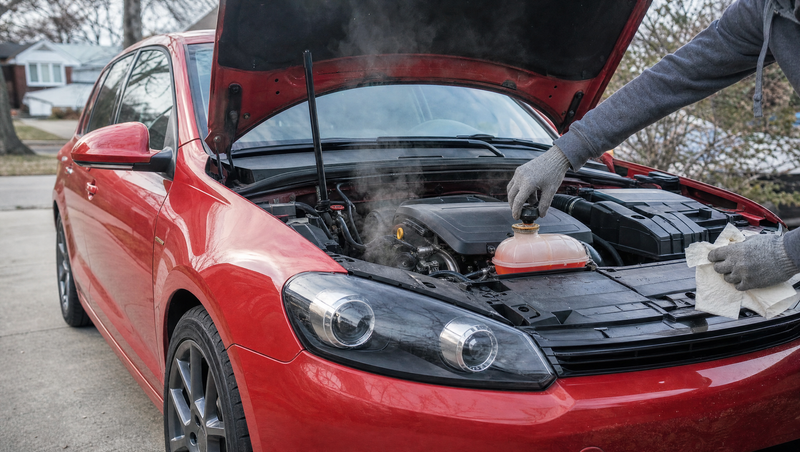 Compacte propulsion rouge capot ouvert dans une allée, main gantée ouvrant le vase d'expansion du moteur turbo lors d'un contrôle avant achat d'une BMW Série 1 F20 d'occasion
