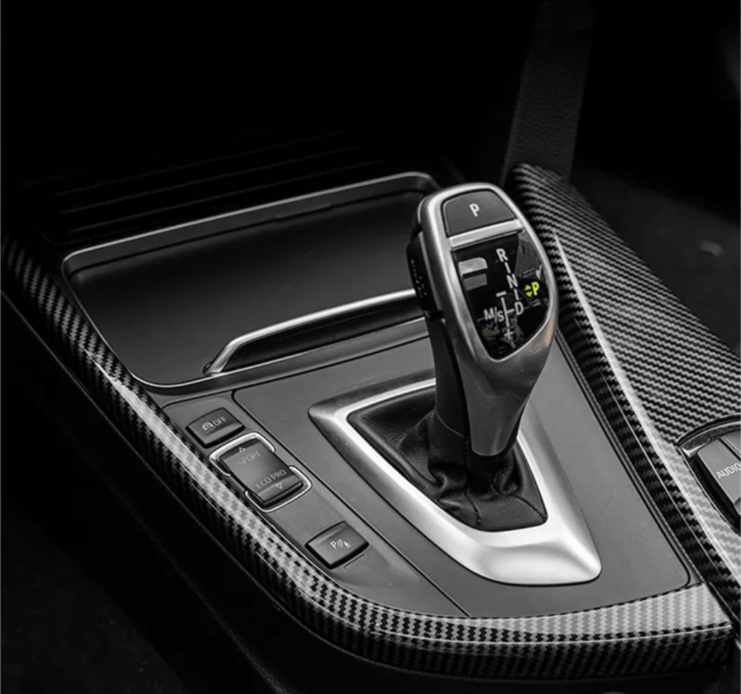 https://cdn.shopify.com/s/files/1/0565/4957/2747/products/Insert-interieur-carbone-entourage-levier-de-vitesse-pour-BMW-Serie-1-F20-2011-2019.png?v=1761576972